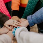 person in red sweater holding babys hand